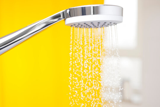 Close-up of flowing water drops from a shower head in a bright bathroom