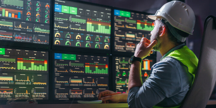 Engineer operator and computer screens with modern following production system Industry 4.0 Head engineer of factory control process production line uses UI interfaces