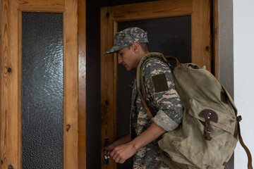 military man with a backpack goes out the door