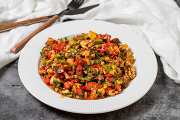 Gavurdagi salad on dark background. Turkish cuisine appetizer flavors. Salad made with walnuts, tomatoes, green peppers, onions, parsley and cucumbers. close up