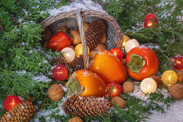 Christmas (New Year) composition with branches of coniferous trees, fruits, nuts, fir cones, luminous garland and gift basket