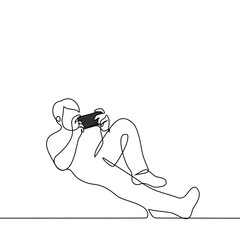 man lies with phone or game console - one line drawing vector. mobile online games concept