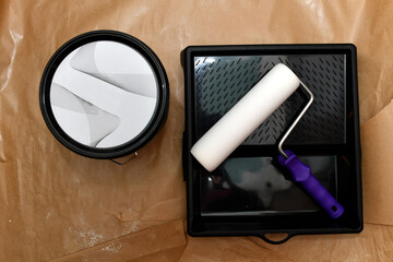 top view of foam roller on paint tray with waterproof paper. concept painting at home or in the...