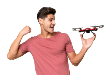 Young caucasian man holding a drone over isolated background celebrating a victory
