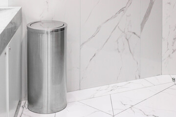 Metal trash bin indoors on a light background