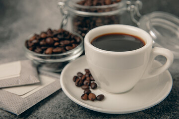 Drip coffee bags, coffee beans and a white cup on a texture table. Ground coffee for brewing in a cup, paper bag drip coffee filter packaging. Place to copy. Place for text.