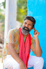 Indian farmer talking on smartphone at home