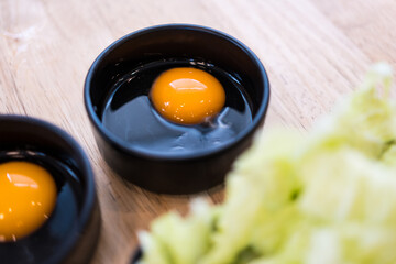 Fresh raw egg in black bowl. Selective focus