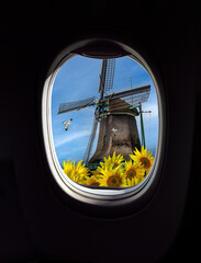Landscape with old hollands windmill with sunflowers, view from porthole window of an airplane. Concept for travel agensy, airlines company or passengers airway transportation in Netherlands.