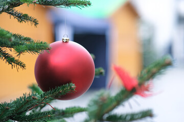 Nahaufnahme einer weihnachtlich geschmückten Tanne mit einer großen roten Christbaumkugel in...