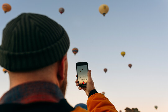 A man take a pictures of hot flying balloons in Cappadocia with his cell phone