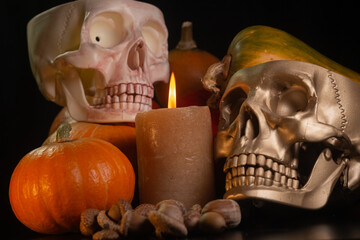 Yellow-orange pumpkins with candles and skulls on a black background the concept of Halloween and the autumn harvest of pumpkin close-up copyspace from above