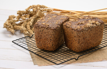 Two fresh loaves of rye bread on the background of spikelets.