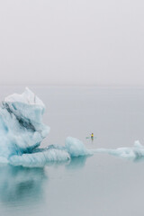 Persona haciendo Padel Surf en un lago helado con icebergs en Islandia