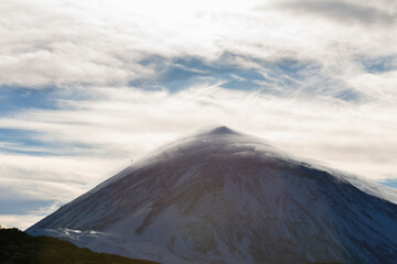 Silhouette of Teide volcano at sunset. Silhouette of volcano with white clouds. Counterpoint of a mountain. Tenerife, Canary Islands, Spain.