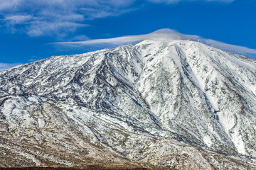 snow-capped volcano of Teide in winter. Snowy mountain with clear blue sky with some frayed clouds. Tenerife, Canary Islands, Spain.