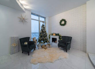 Beautiful light interior of living room with decorated Christmas tree and gifts. Candles on fireplace. Wreath on brick wall. Two cozy armchairs.