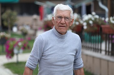 an older man with a dangerous look. a man looks angrily at someone. the man has gray hair and wears glasses. He is 80 years old and looks much younger. Angry face,angry look