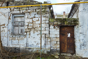 An old leaning dilapidated residential building. Poor living conditions of people.