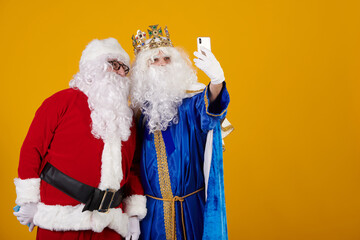 Santa Claus and Wise Man taking a selfie with a mobile phone as friends