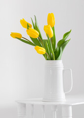 yellow tulips in vase on white background