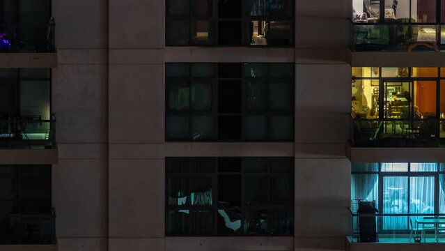Windows of apartment building at night timelapse, the light from illuminated rooms of houses with chairs on balcony. Urban landscape of the skyscrapers