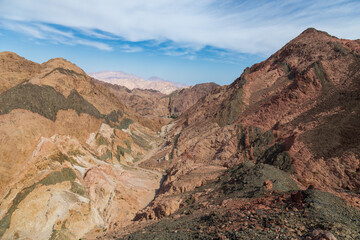 Mountain landscape with layered colorful rock formations in daytime sunlight, Dahab, Egypt