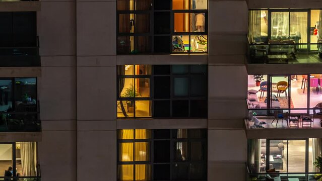 Windows of apartment building at night timelapse, the light from illuminated rooms of houses. Urban landscape of the glowing skyscrapers
