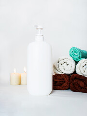 Obraz na płótnie Canvas massage oil in a large plastic bottle with a dispenser, towels stacked in a pile, and scented candles, a spa room, a bathroom,antiseptic, beauty salon, 