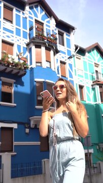 Lifestyle, blonde woman in a blue colorful facade house in summer sending a voice note