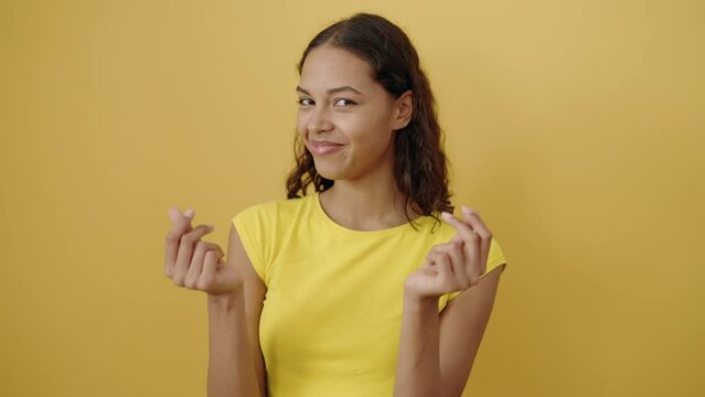 Young african american woman smiling confident doing spend money gesture over isolated yellow background