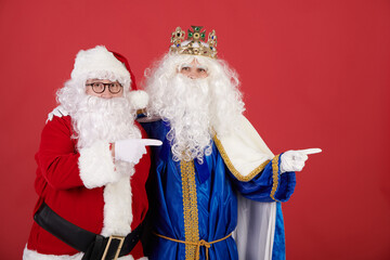 A Wise Man and Santa Claus pointing at a billboard and looking at the camera