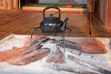 An old kettle is placed on a firewood stove