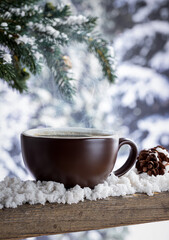Obraz na płótnie Canvas Steaming hot cup of coffee with winter background