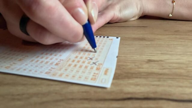Picking lotto numbers.
Lottery playing cards. A woman's hand crosses out the numbers.
