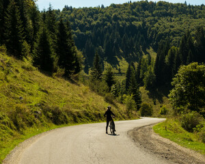 Girl with MTB in the middle of the road in the Romanian Mountains. Greet bike roads in the Bucegi Mountains. Mountain Biking in rural environment with fresh air and a lot of green.