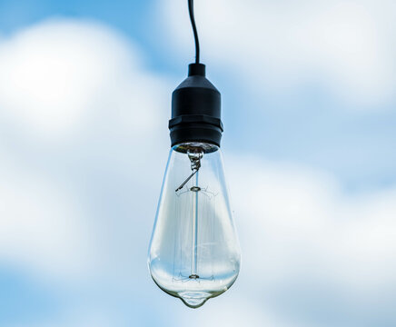 A light bulb in the blue sky . A beautiful summer with a glass bulb turn off. Nice element in the garden. Outdoor bulb for good light . Energy is save. Led bulb.