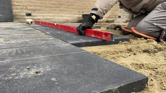 A worker laying paving slabs on the street 