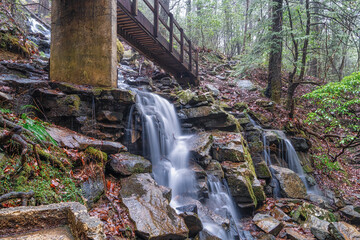 A hiking trail foot bridge crossing a mountain stream waterfall in late autumn. The Fiery Gizzard Trail on the Cumberland Plateau in Tracy City Tennessee USA.
