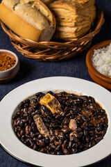 Beans and pork, typical food from Brazil, on a white plate.