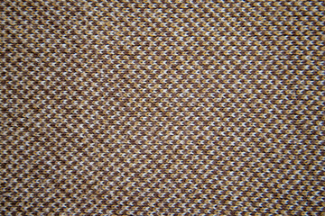 Knitted pattern of brown, white and orange yarns. Brown knitted fabric. Background for design, lettering or illustration