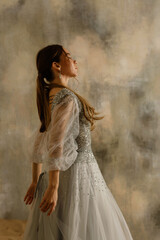 Fototapeta na wymiar a girl in a dress against a shabby wall