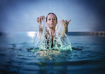 Beautiful woman splashing water in swimming pool.