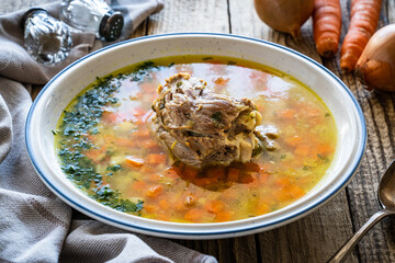 Fresh spring soup with big piece of meat on wooden table
