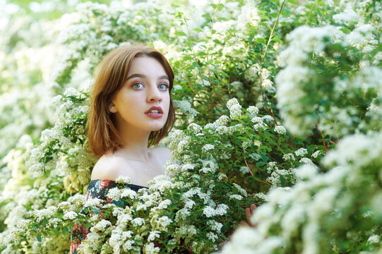 Young beautiful girl on a summer day among flowering trees
