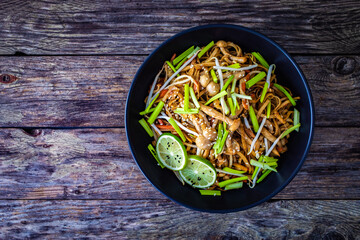 Asian food - Chow Mein noodles, stir fried vegetables, soy sauce and shimeji mushrooms on wooden...