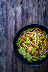 Asian food - Chow Mein noodles, stir fried vegetables, soy sauce and shimeji mushrooms on wooden table
