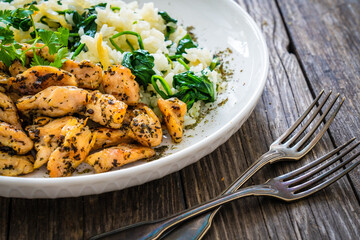 Fried chicken nuggets with white rice and spinach on wooden table
