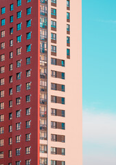 A red and beige apartment building on a blue sky background. Sunset rays of the sun