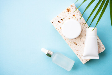 Natural cosmetic product with palm leaves on blue background. Top view with copy space.
